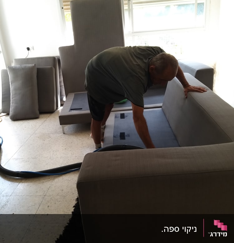 אדם מנקה ספה עם שואב אבק